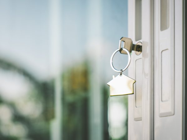 House model and key in home with light from window. Real estate agent offer house, property insurance and security, affordable housing concepts
